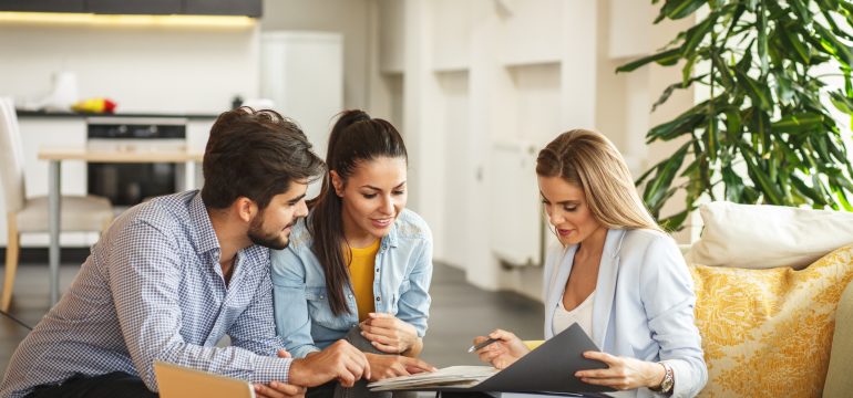 Two real estate professionals meeting with a landlord to discuss essential property care for their investment.