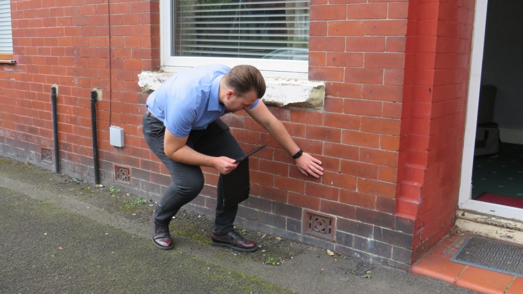 Rentokil Property Surveyor inspecting an external air brick vent on a brick wall.